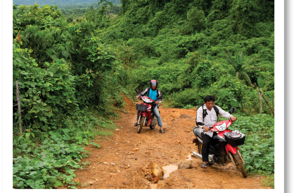 Two men riding motorbikes up a hill