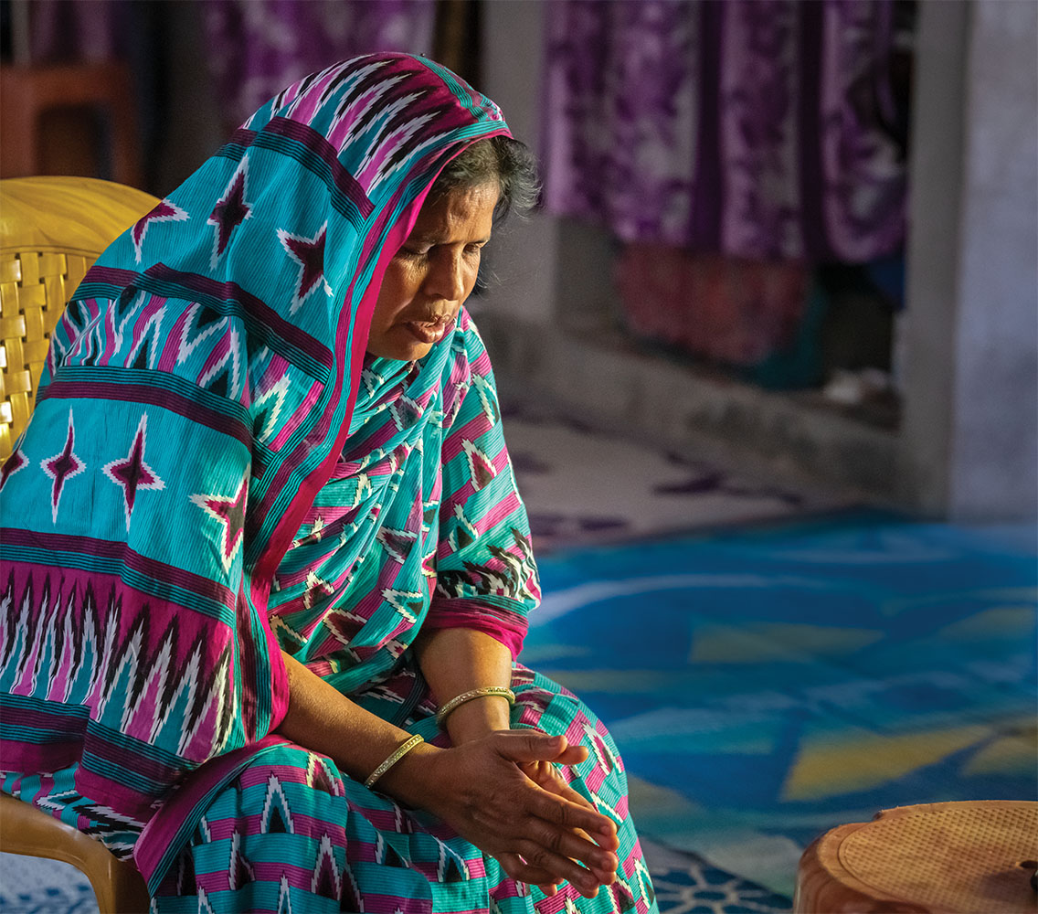 Woman with teal and red head covering praying